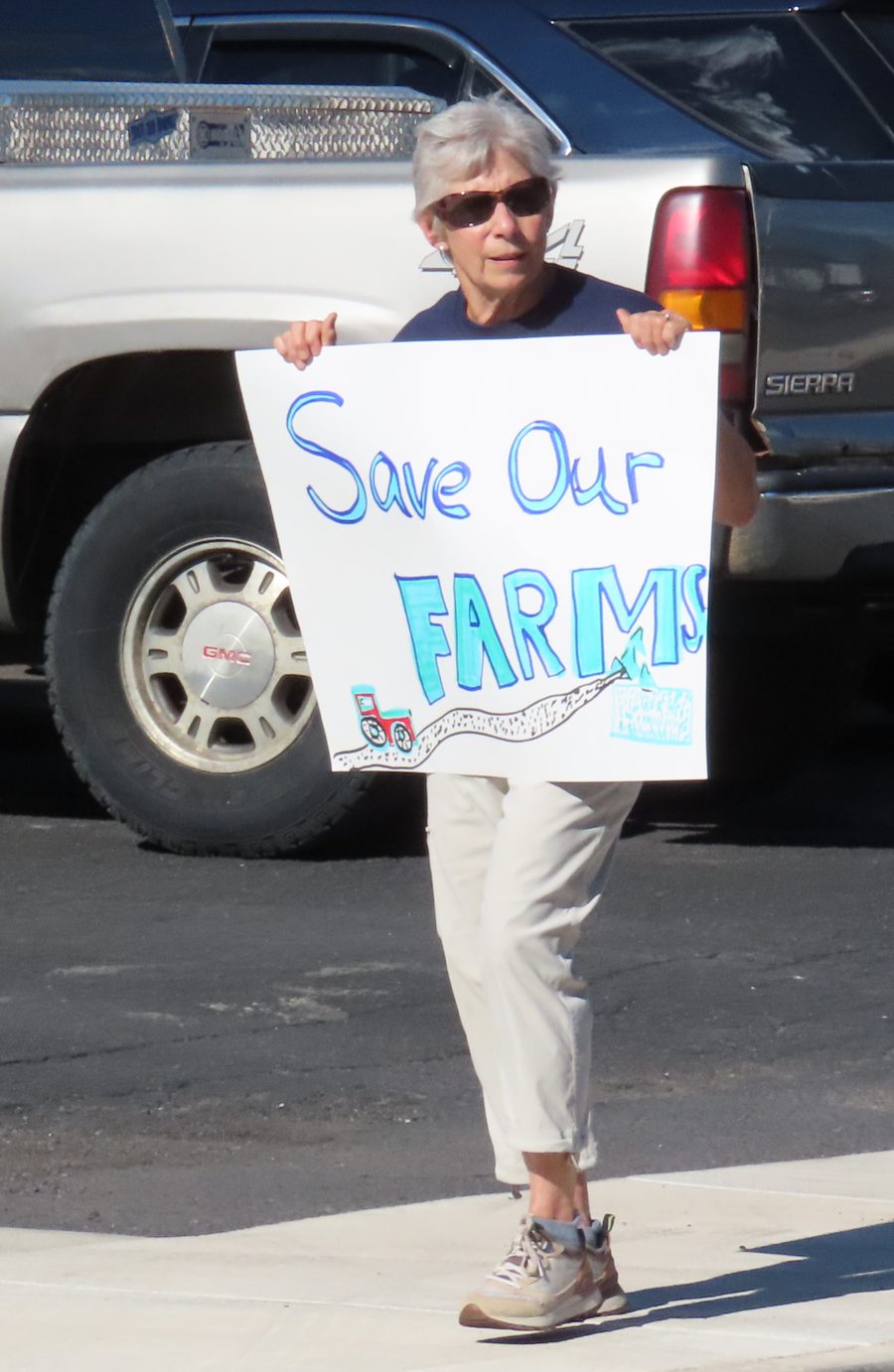 Hardy County resident holding a hand-painted Save Our Farms sign